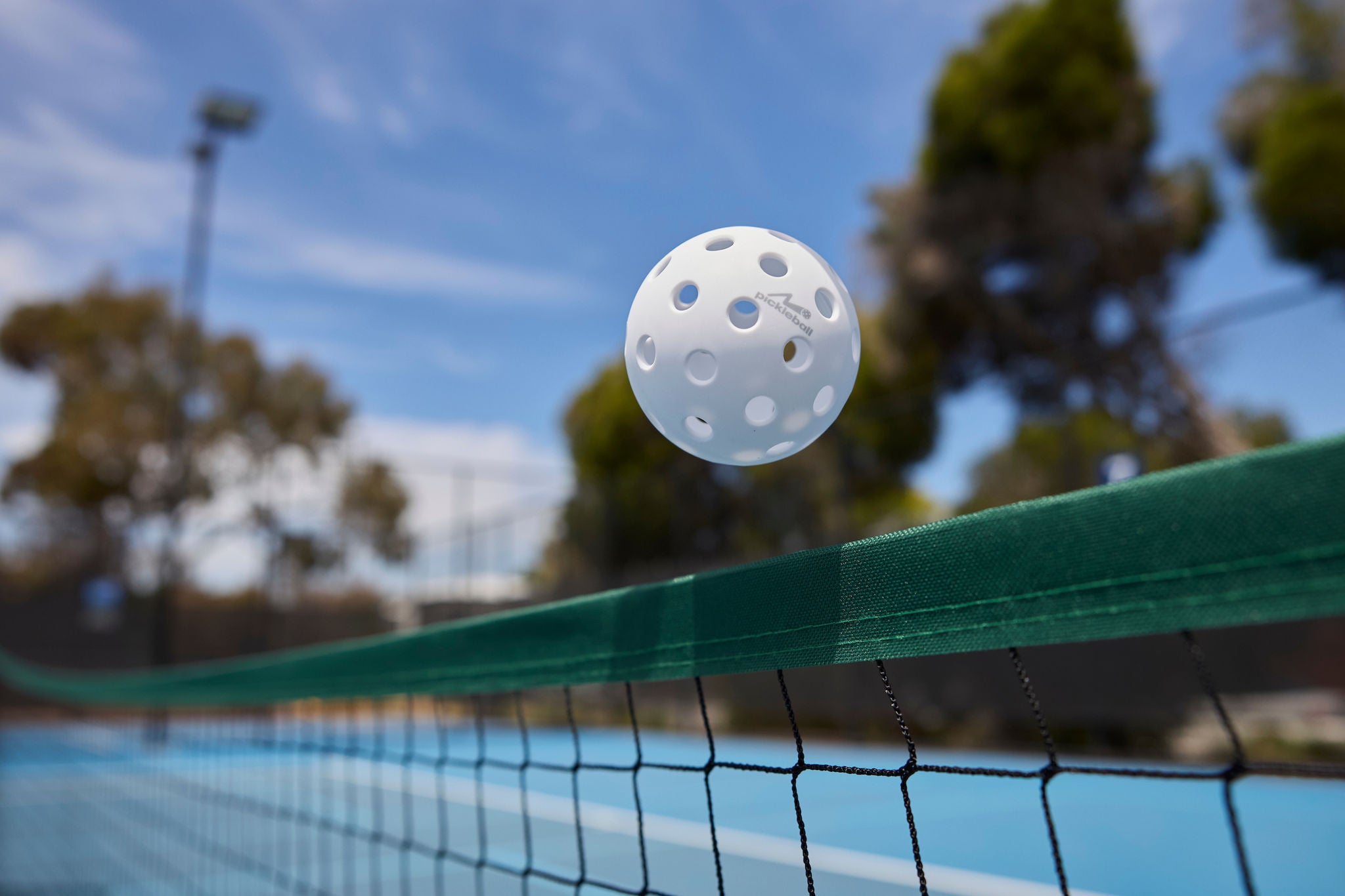 A pickleball ball floating over the net.