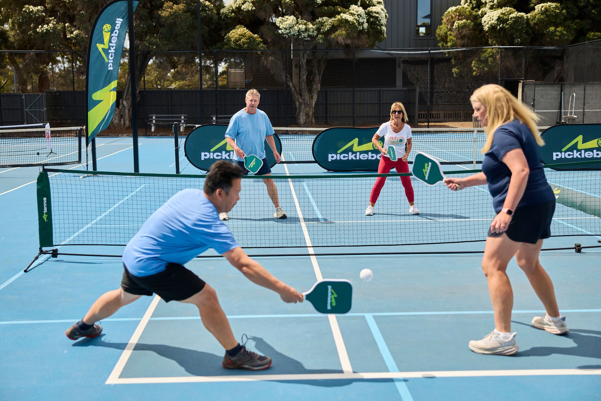 A fast-paced game of mixed doubles on a compact pickleball court with a lower net than tennis.
