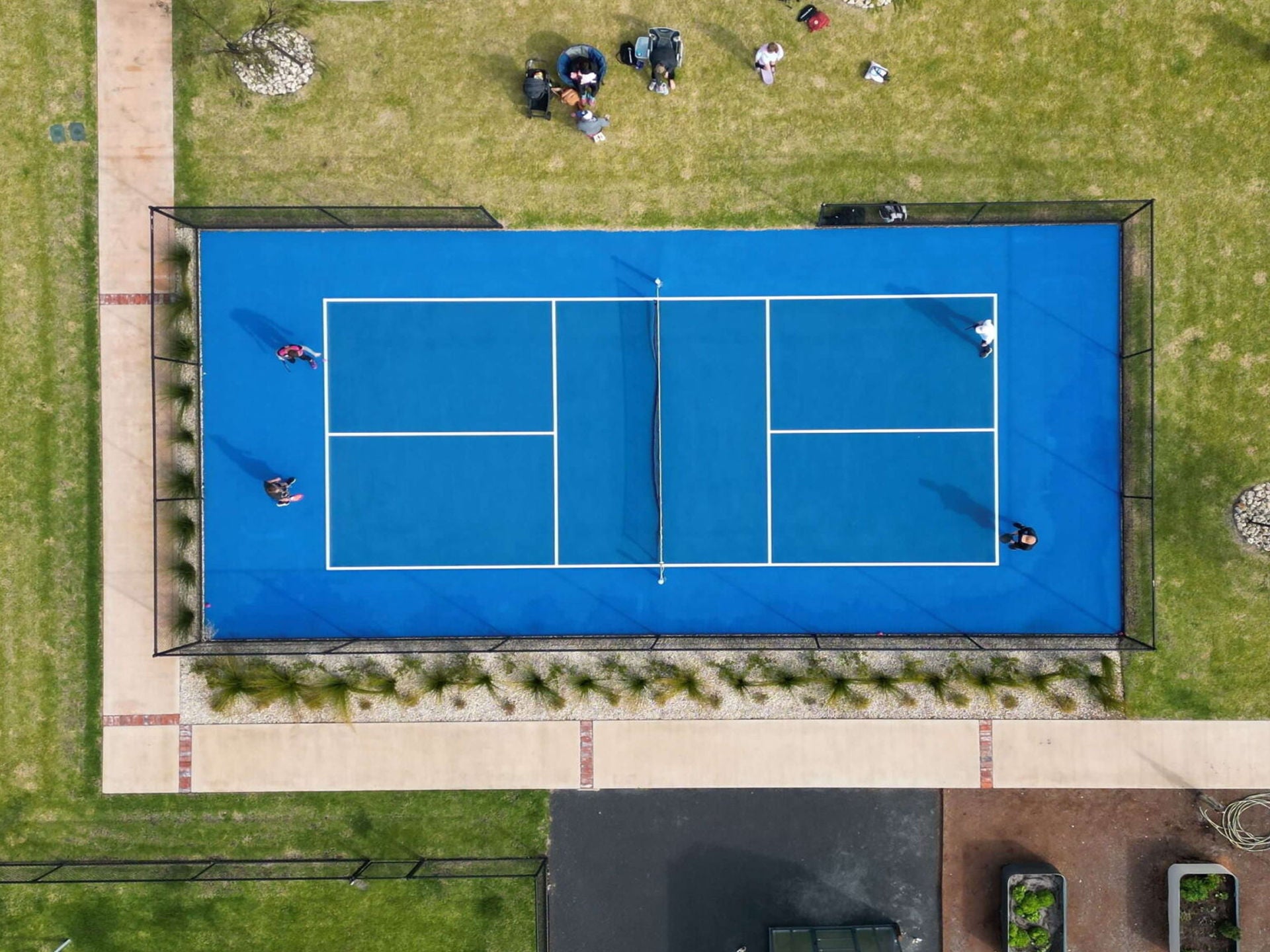 Aerial shot of a pickleball court with a doubles game playing overlooked by spectators