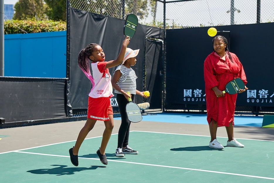Two kids and their mum playing pickleball.