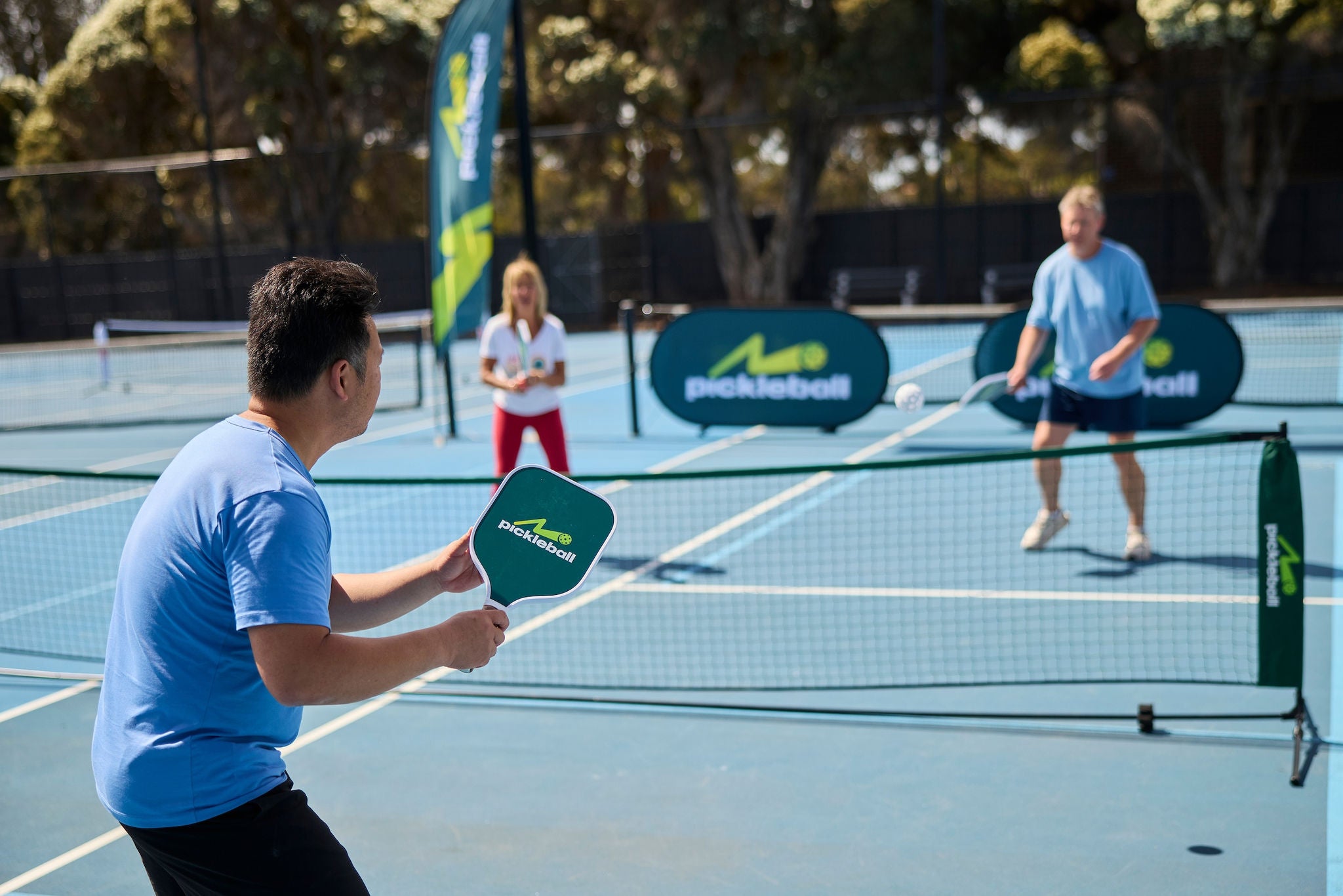 A pickleball player prepares to return a ball after it successfully bounces in the service box.