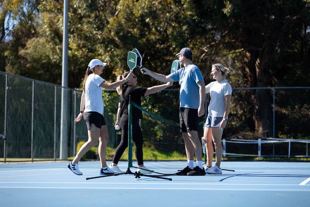 A group of four adults hitting padels at a temporary pickleball court set up at their local tennis club