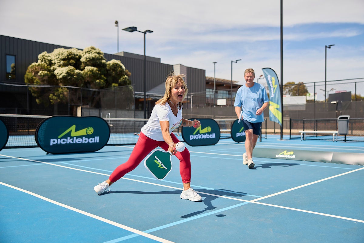 Lady returns shot in seniors mixed pickleball game